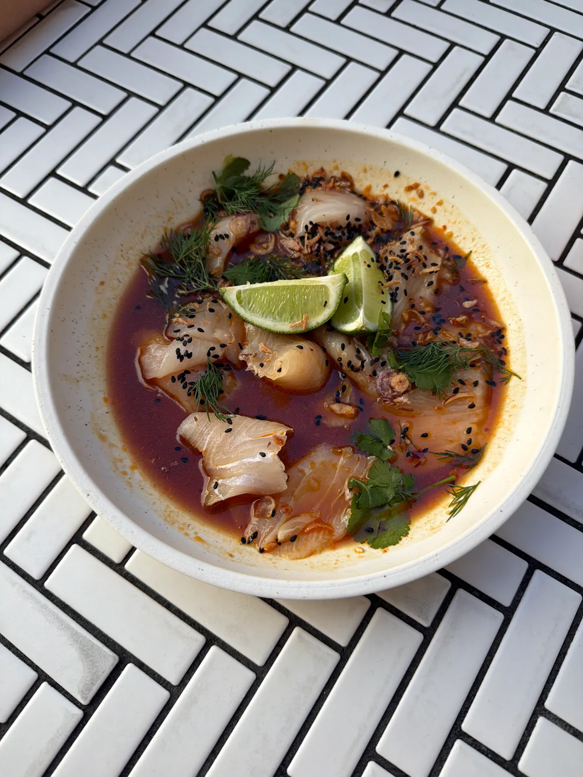 Fresh sliced kingfish in ginger-soy sauce with black sesame, fried shallots, lime, coriander and dill